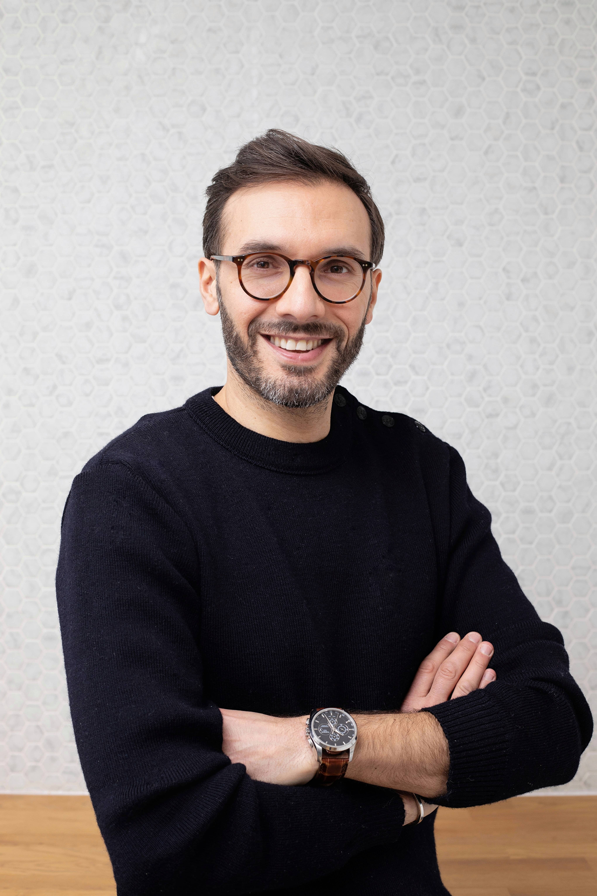 Portrait de Sélim Niederhoffer, de face, avec un pull noir et des lunettes, bras croisés